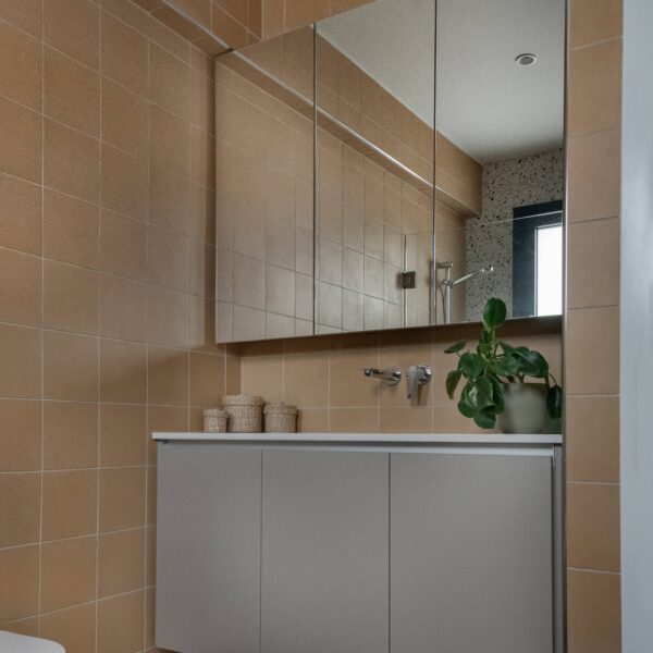 nicosia migliore no.10, newly built house Toilet room finished in sunny yellow terrazzo floor tiles, wall‑mounted black sink and tap, large format neutral wall tile to balance colour and pattern.