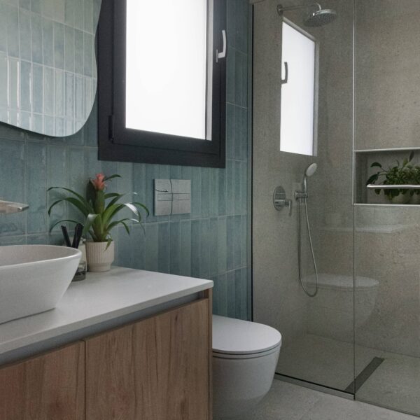 nicosia migliore no.10, newly built house Shower area clad in bold blue terrazzo tiles with yellow aggregate highlights, frameless glass screen, and black ceiling‑mounted rainfall showerhead