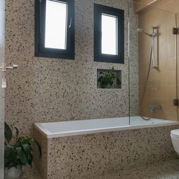 nicosia migliore no.10, newly built house Toilet room finished in sunny yellow terrazzo floor tiles, wall‑mounted black sink and tap, large format neutral wall tile to balance colour and pattern.